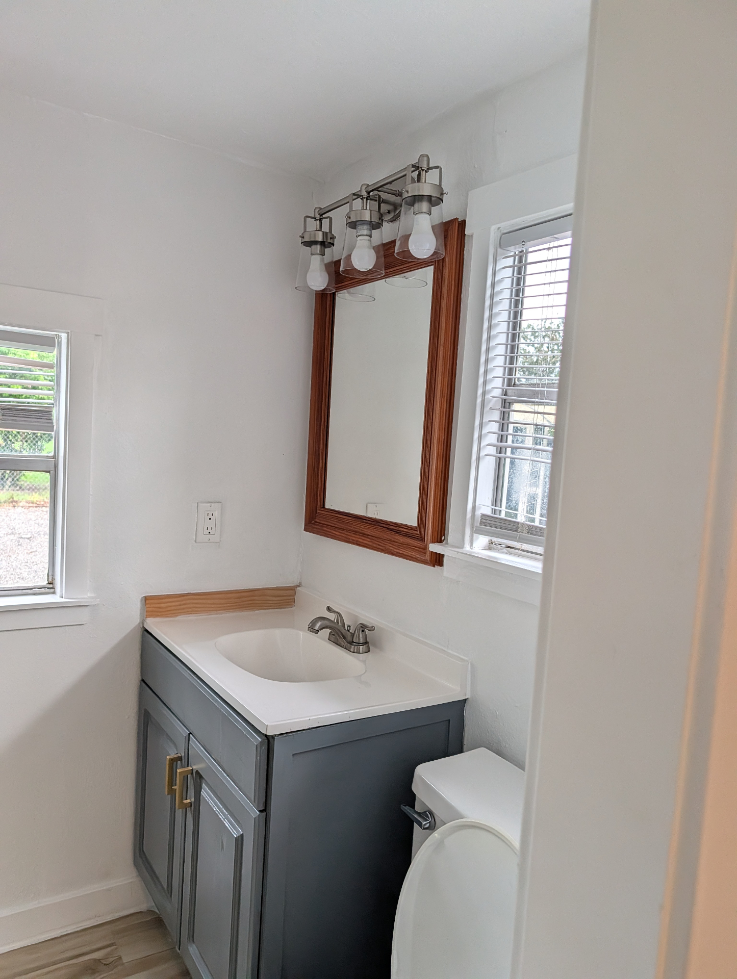 Small Tampa bathroom with refinished gray vanity, new sink and wood-framed mirror